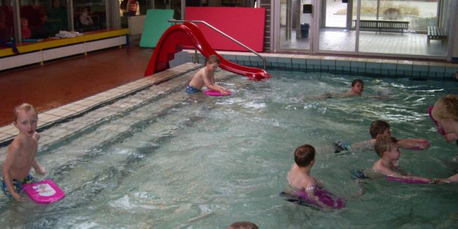 Kinder im Nichtschwimmerbecken mit Schwimmbrettern